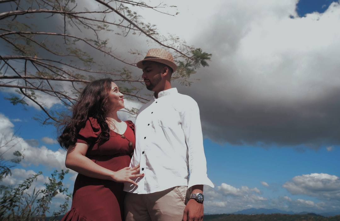 a man and a woman standing next to each other under a cloudy sky