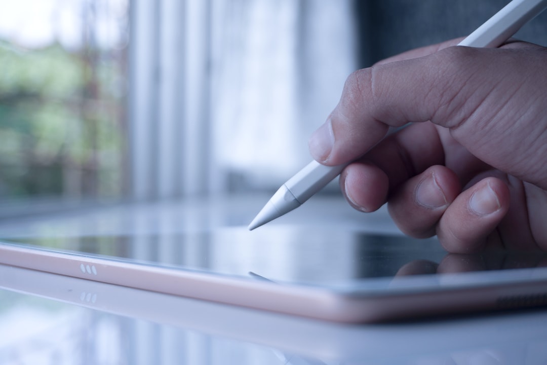 a person holding a pen and writing on a tablet