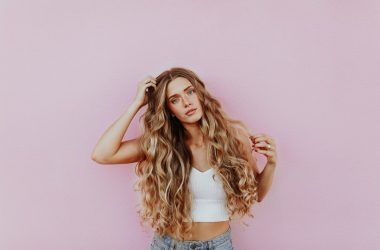 woman standing next to pink wall while scratching her head