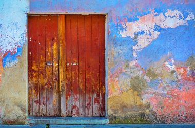 red wooden door of blue, red, and brown painted wall