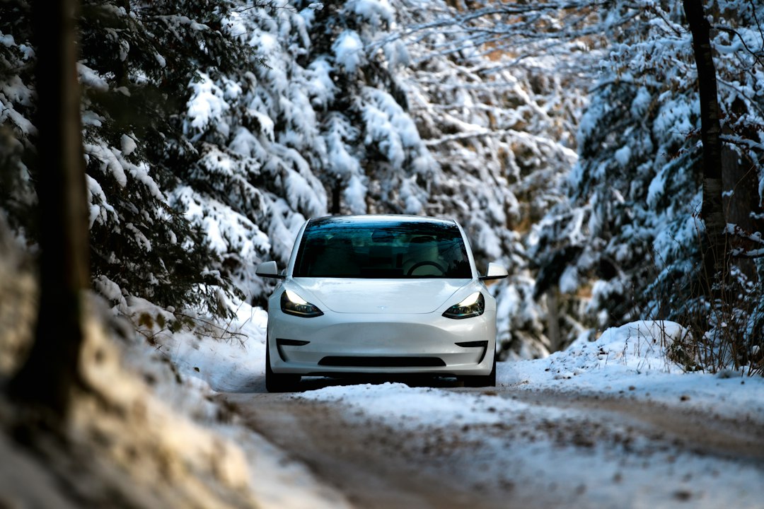 a white car driving down a snow covered road