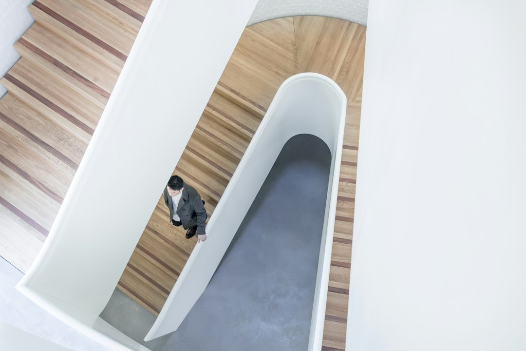 person stepping down on brown wooden stairs aerial photography