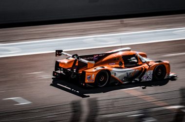 an orange race car driving down a race track