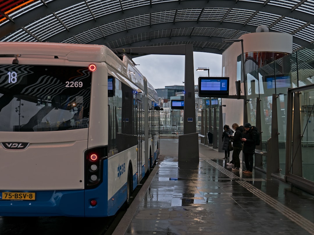 a white and blue bus parked at a bus stop