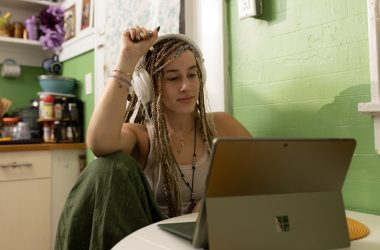 a woman with dreadlocks sitting in front of a laptop computer