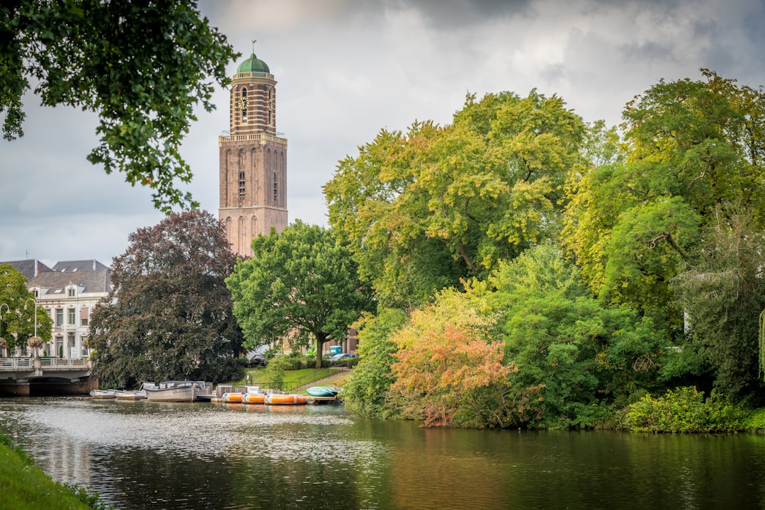 brown concrete building near green trees and river during daytime