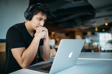 man wearing headphones while sitting on chair in front of MacBook