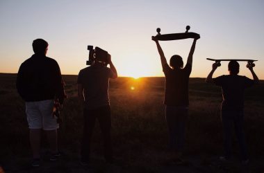 group of people holding skateboards under sunset