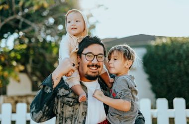 man in white shirt carrying girl in gray shirt