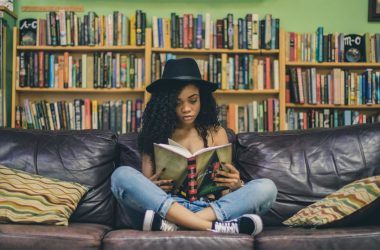 woman reading a book while sitting on black leather 3-seat couch