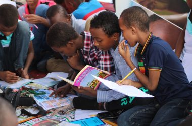 boy in blue and white plaid shirt reading book