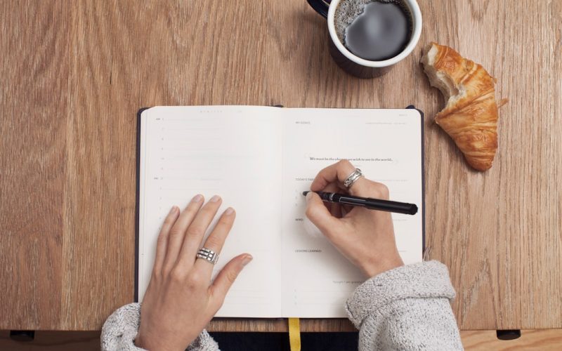 person writing on a book