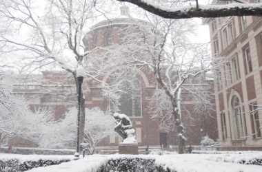 a snow covered campus with a statue in the foreground