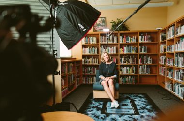 woman sitting on armless chair with light between bookcases in room