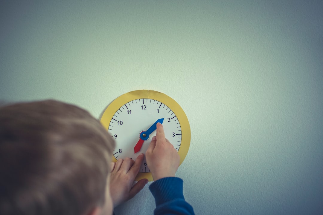 person in blue long sleeve shirt holding white round analog wall clock