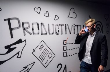 man holding smartphone looking at productivity wall decor