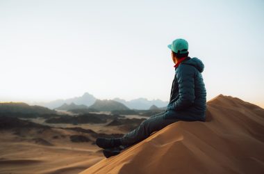 a person sitting on top of a sand dune