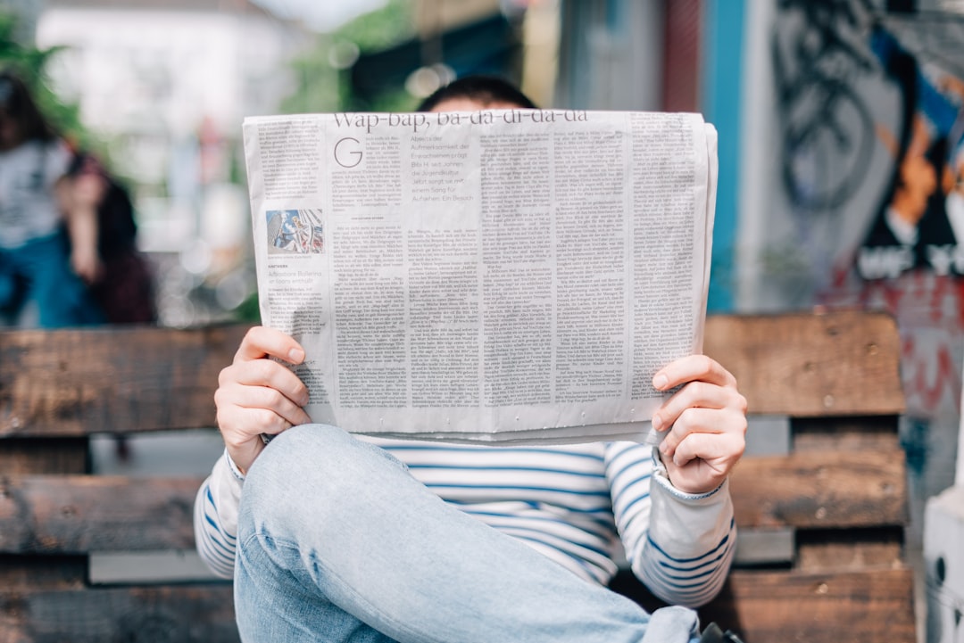 man sitting on bench reading newspaper