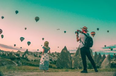 man taking photo of hot air balloons