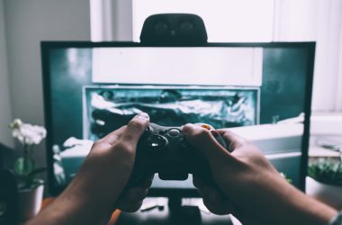 person holding game controller in-front of television