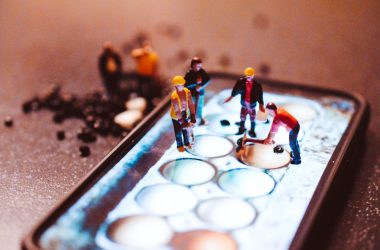 tiny model construction workers, working on a mobile phone screen