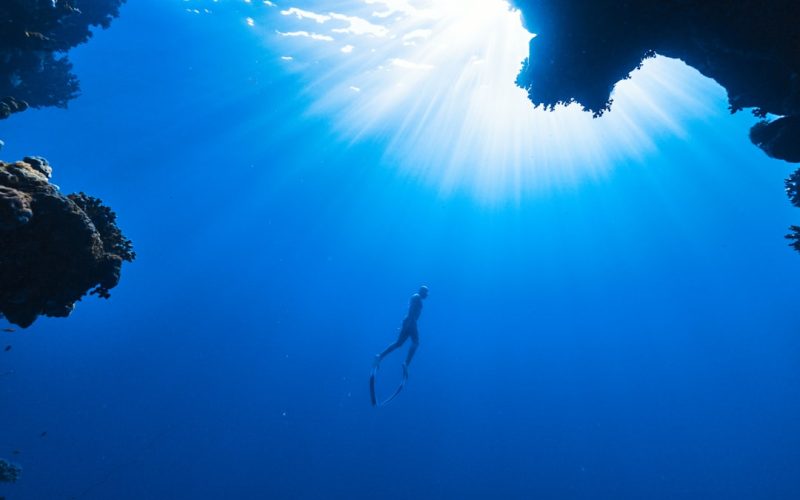 a person swimming in the ocean near a cave