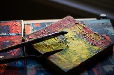paintbrush resting on square multicolored painted block