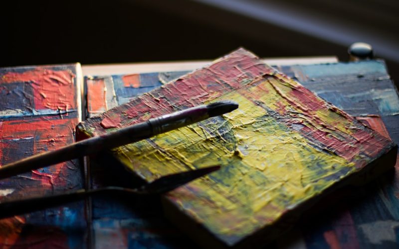 paintbrush resting on square multicolored painted block