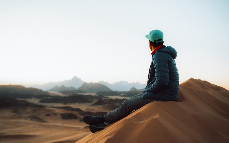 a person sitting on top of a sand dune