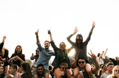 three men carrying women surrounded by many people during daytime