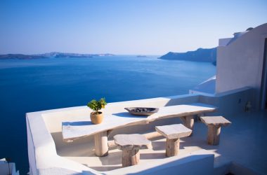 bench and dining table near body of water under calm sky