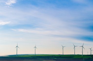 white windmills on green grass field under white clouds and blue sky
