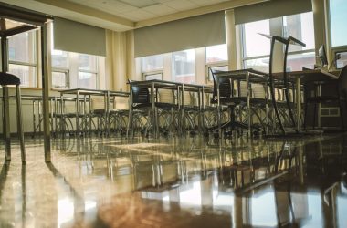 An empty classroom with tables and chairs.