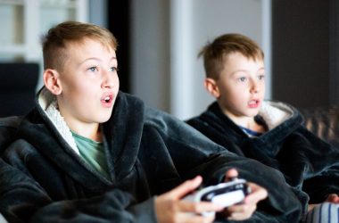 two young boys sitting on a couch playing a video game