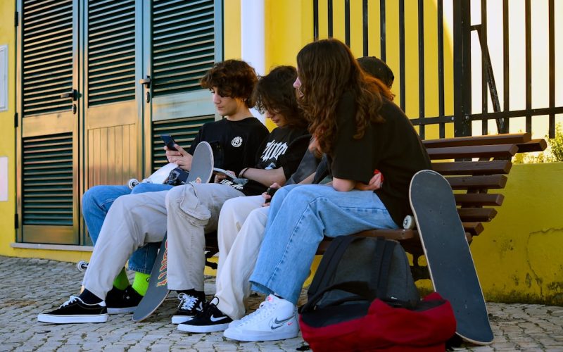 a group of people sitting on a bench with their laptops