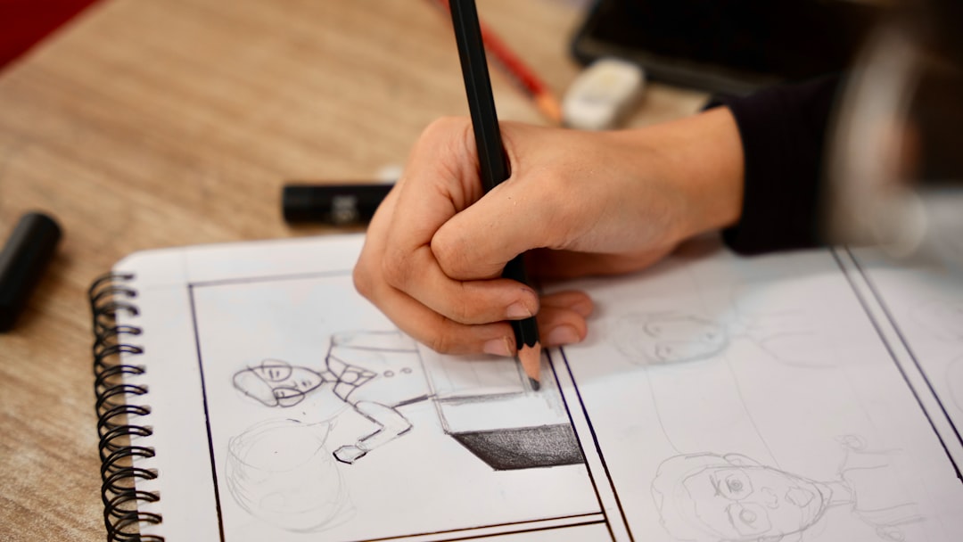 A person holding a pencil and drawing on a book