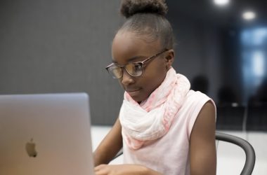a little girl sitting in front of a laptop computer