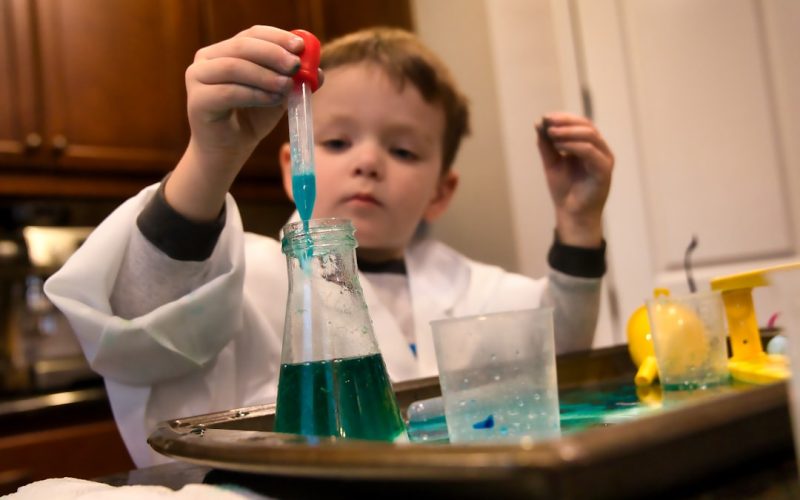 boy in white long sleeve shirt holding red and clear plastic tool