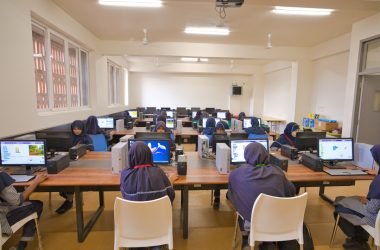 A group of people sitting at desk with laptops