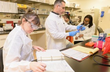 a group of people in lab coats working in a lab