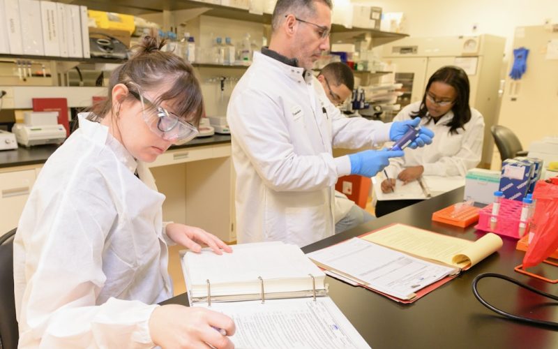 a group of people in lab coats working in a lab