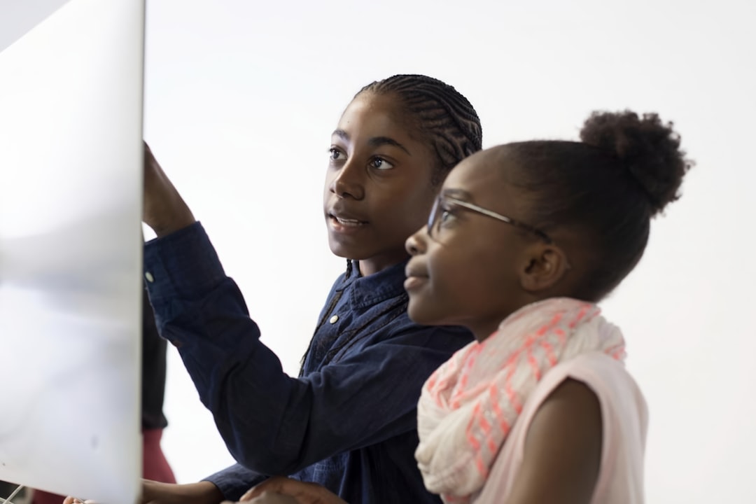 a couple of kids that are looking at a computer screen