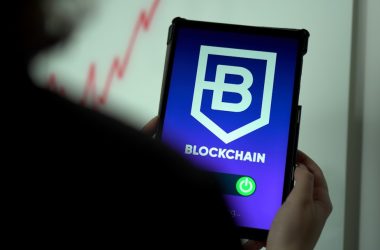 a person holding a cell phone with a blockchain logo on it