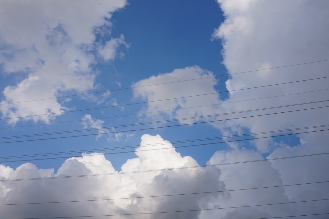 A blue sky with white clouds and power lines