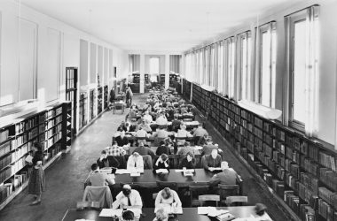 a black and white photo of people in a library