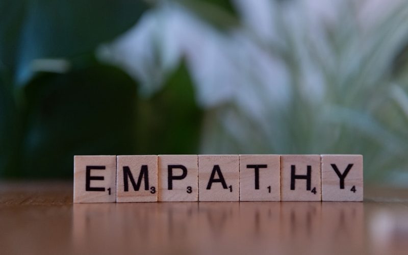 A wooden block spelling the word empathhy on a table