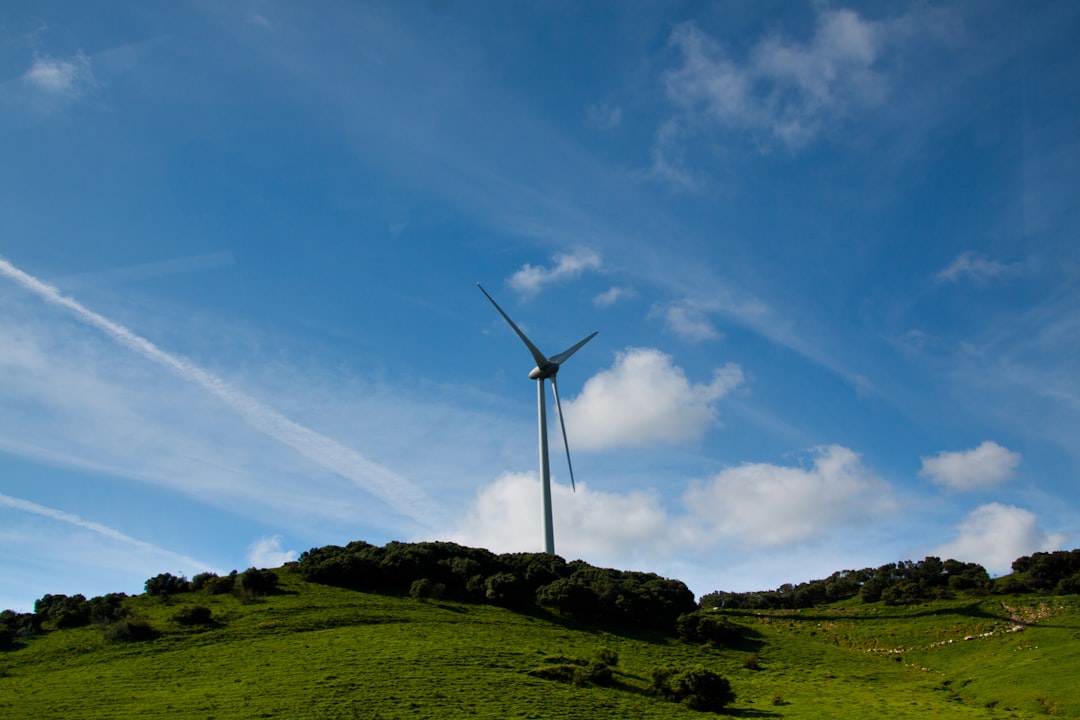 wind turbine on green grass field under blue sky and white clouds during daytime