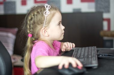 a little girl sitting in front of a computer keyboard
