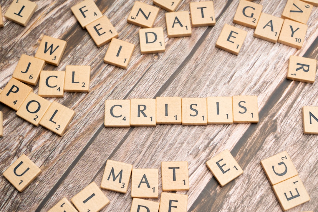 scrabble tiles spelling the word crissis on a wooden surface