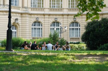 people sitting on green grass field near white concrete building during daytime